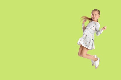 Image of Cute girl jumping on yellowish green background, space for text