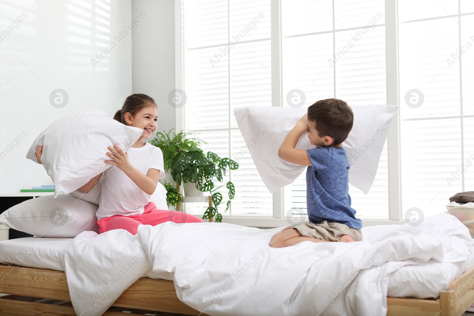 Photo of Happy children having pillow fight in bedroom