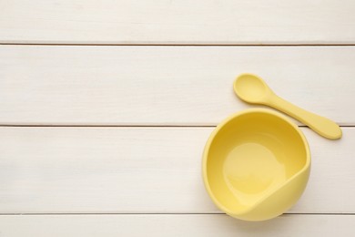 Photo of Plastic bowl and spoon on white wooden background, flat lay with space for text. Serving baby food