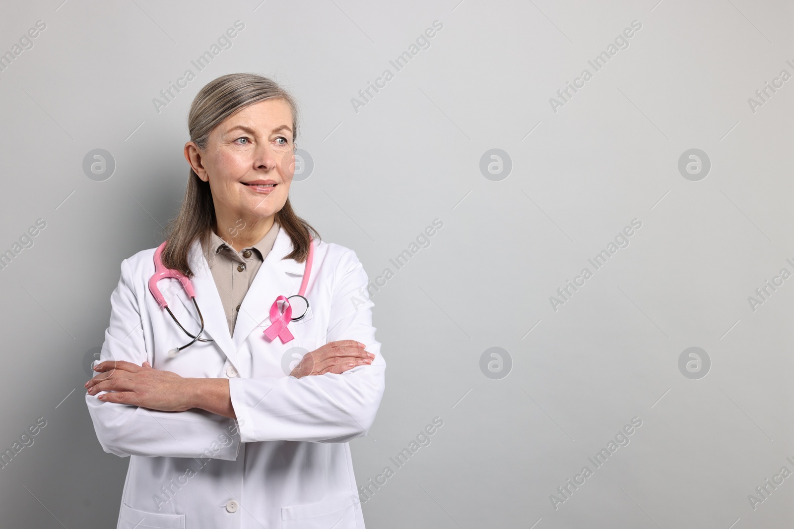 Photo of Mammologist with pink ribbon on gray background, space for text. Breast cancer awareness