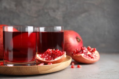 Photo of Pomegranate juice and fresh fruits on grey table, space for text