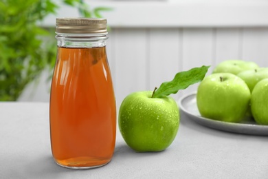 Bottle of apple juice and fresh fruit on table