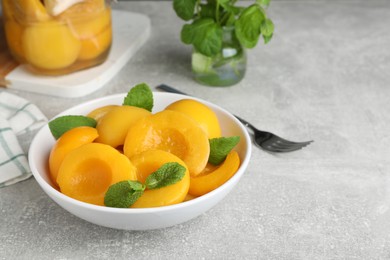 Photo of Canned peach halves in bowl on light table, space for text