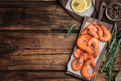 Delicious cooked shrimps served with lemon and spices on wooden table, flat lay. Space for text