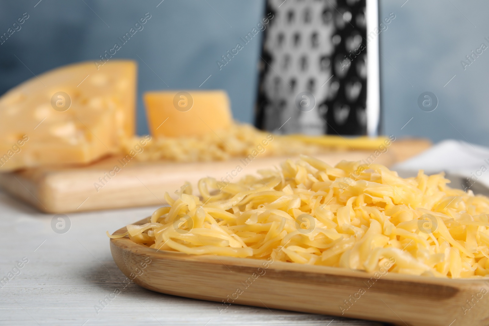 Photo of Delicious grated cheese on white wooden table, closeup