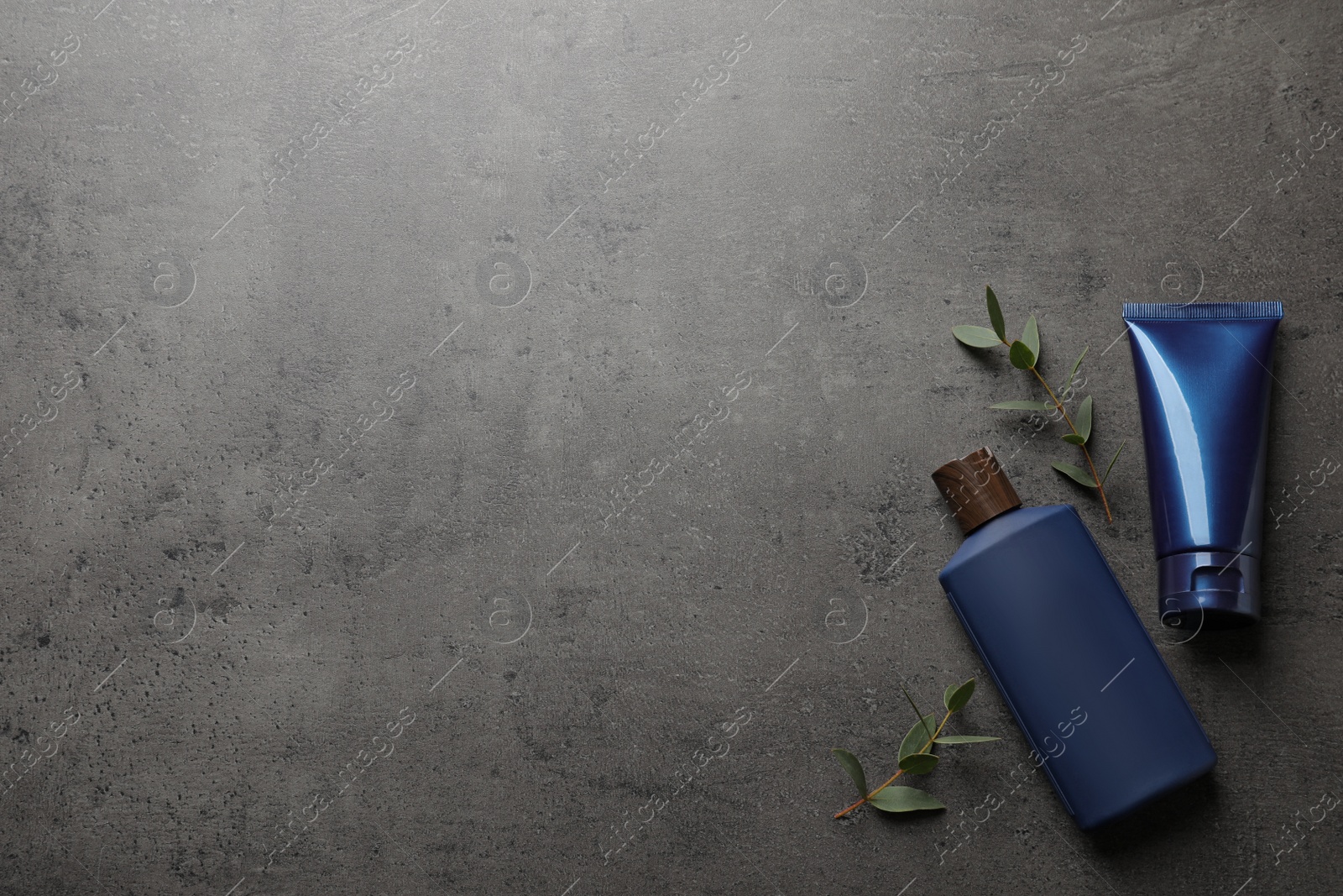 Photo of Men's facial cream, shampoo and green leaves on grey stone table, flat lay. Mockup for design