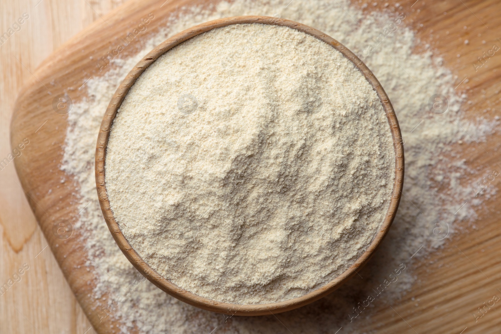 Photo of Quinoa flour in bowl on wooden table, top view