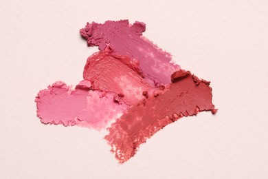 Photo of Smears of beautiful lipsticks on light background, top view