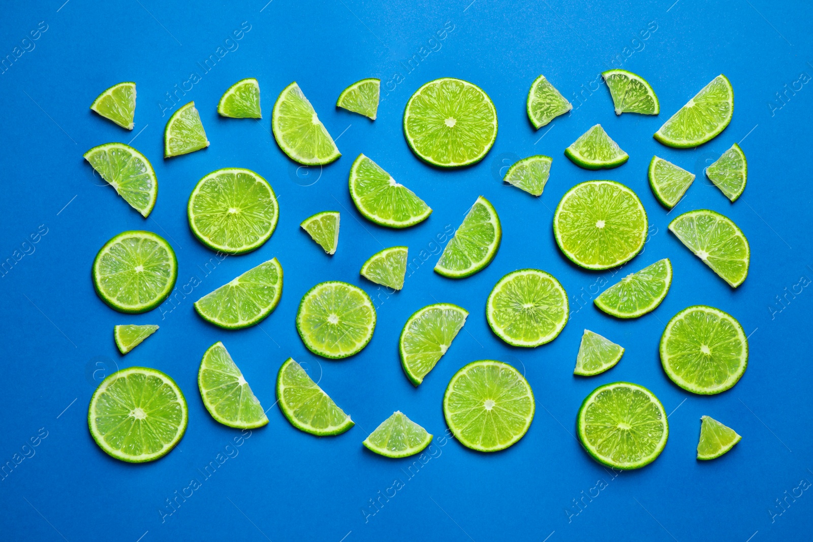 Photo of Juicy fresh lime slices on blue background, flat lay