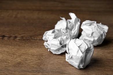 Balls of crumpled paper on wooden table, space for text