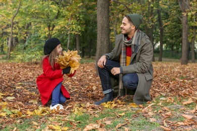Father and his cute daughter spending time together in park. Autumn walk