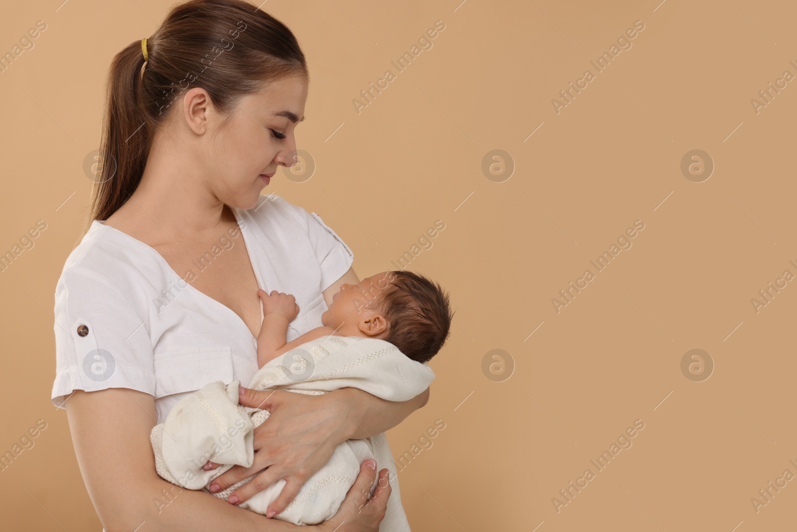 Photo of Mother with her cute newborn baby on beige background. Space for text