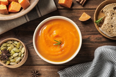 Photo of Flat lay composition with bowl of tasty sweet potato soup on wooden background