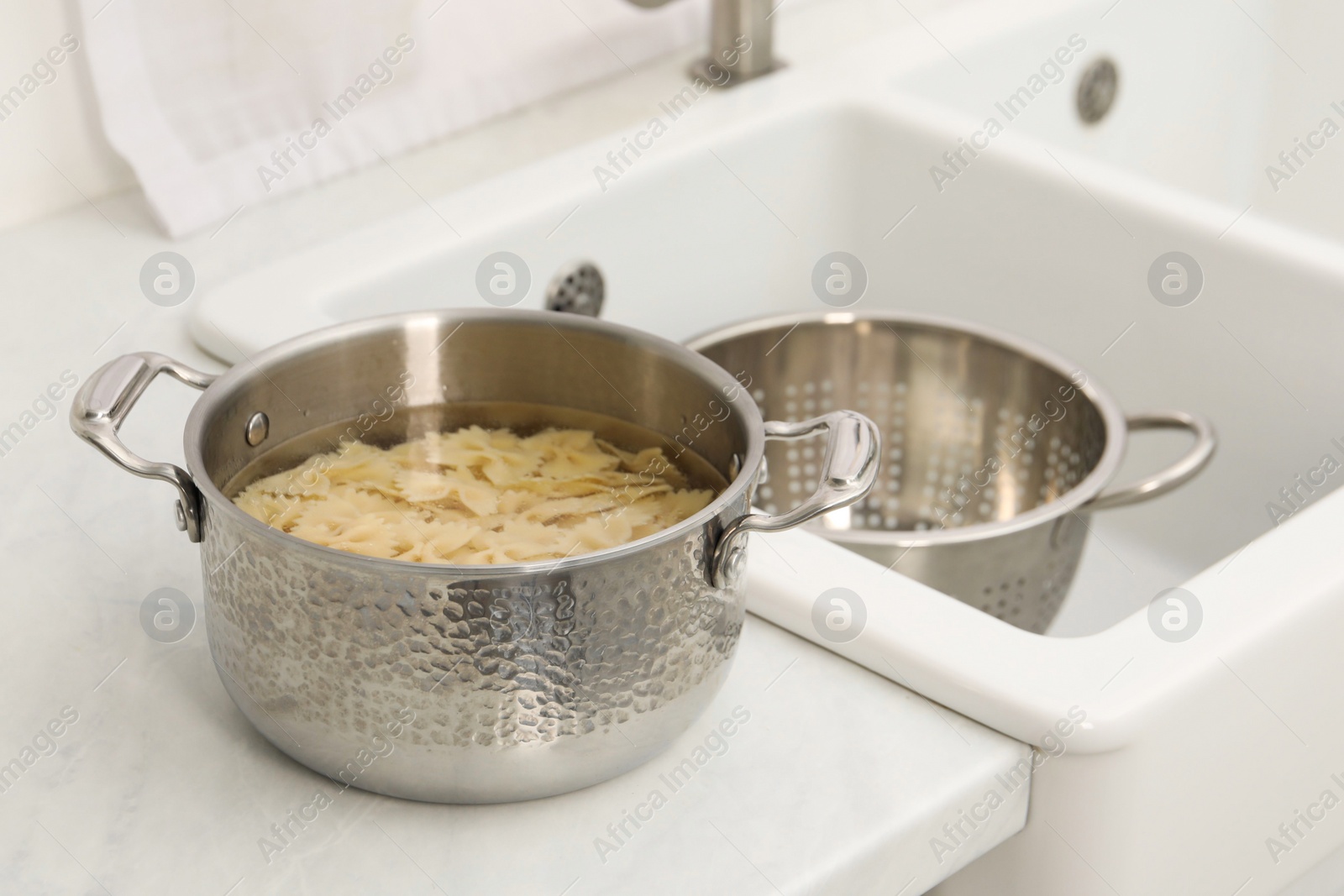 Photo of Cooked pasta in metal pot on countertop near sink