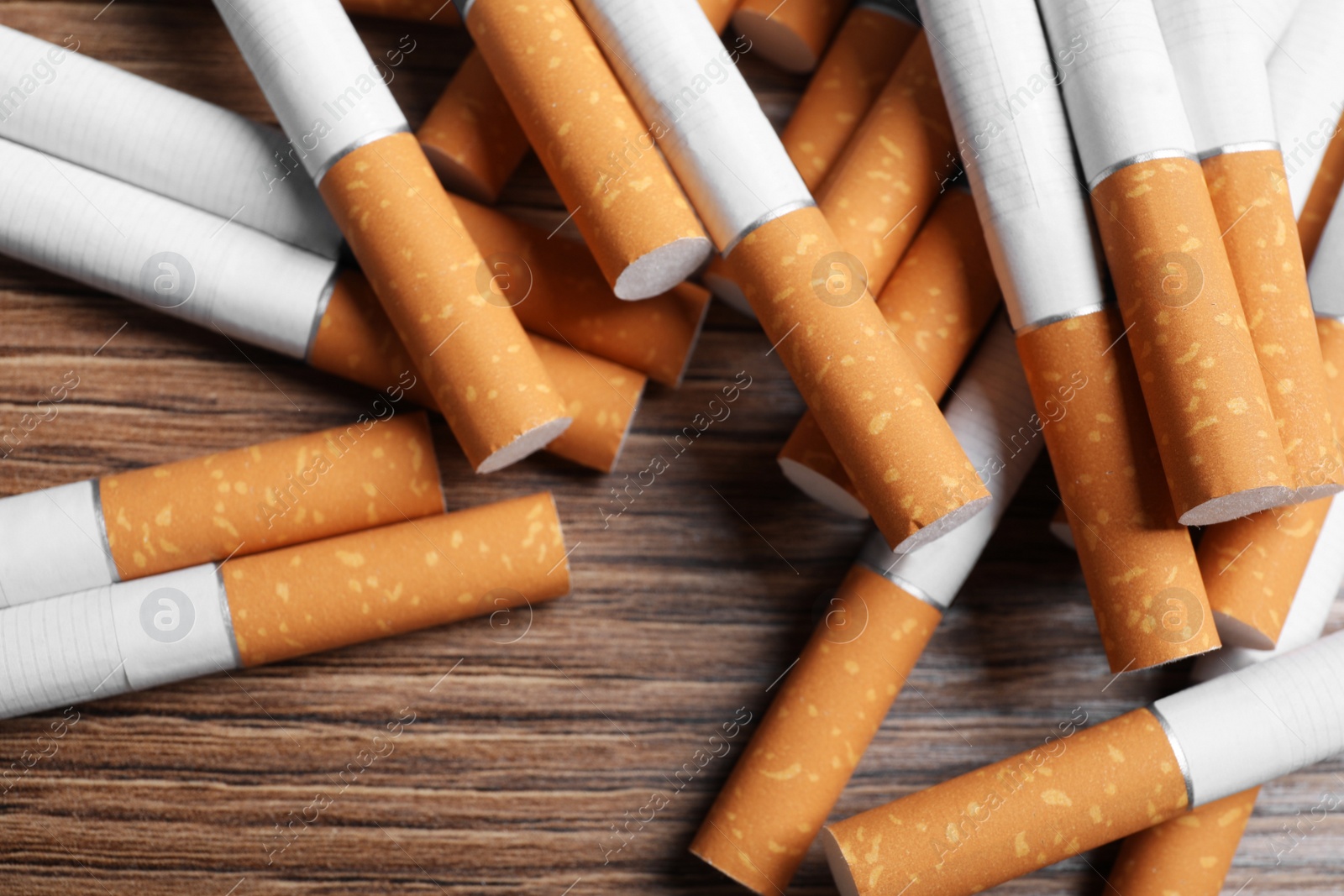 Photo of Pile of cigarettes on wooden table, above view