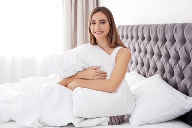 Photo of Beautiful teen girl hugging comfortable pillow in bed at home