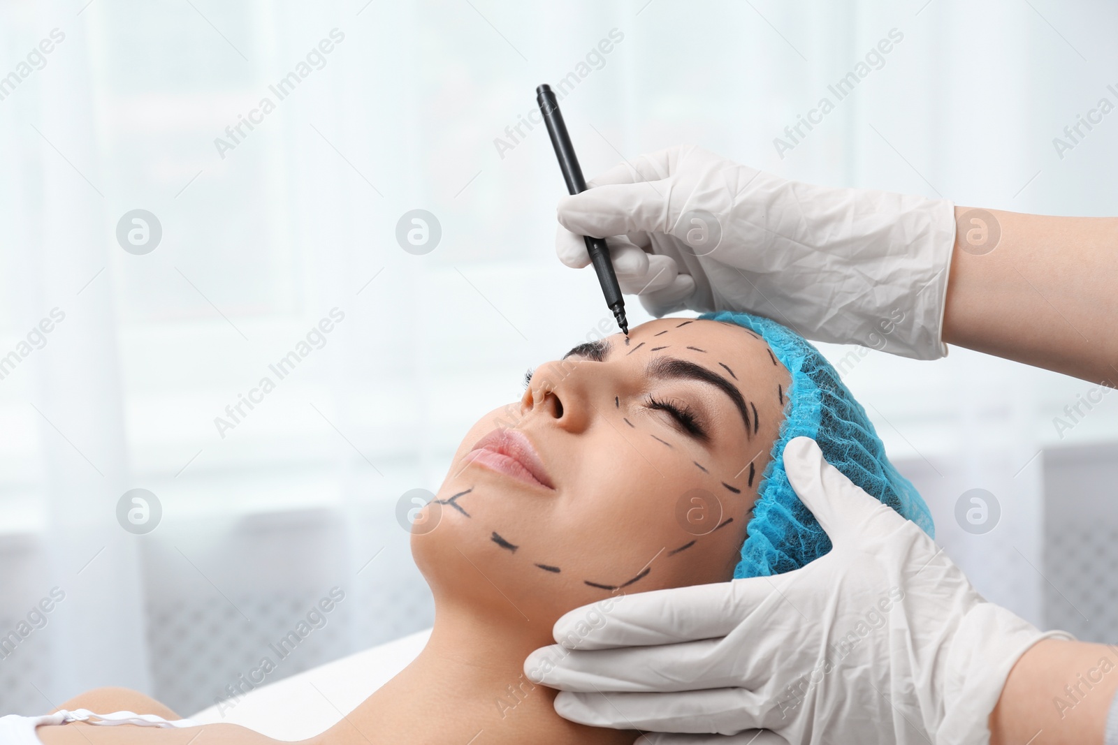 Photo of Doctor drawing marks on woman's face for cosmetic surgery operation in clinic