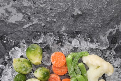 Photo of Different frozen vegetables and ice on black table, flat lay. Space for text