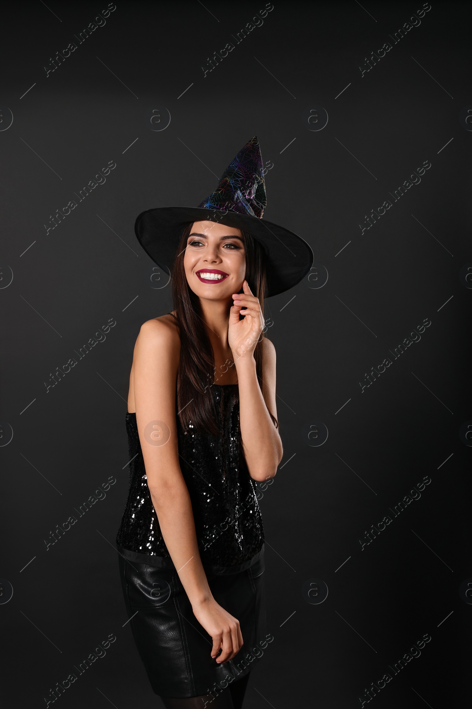 Photo of Beautiful woman wearing witch costume for Halloween party on black background