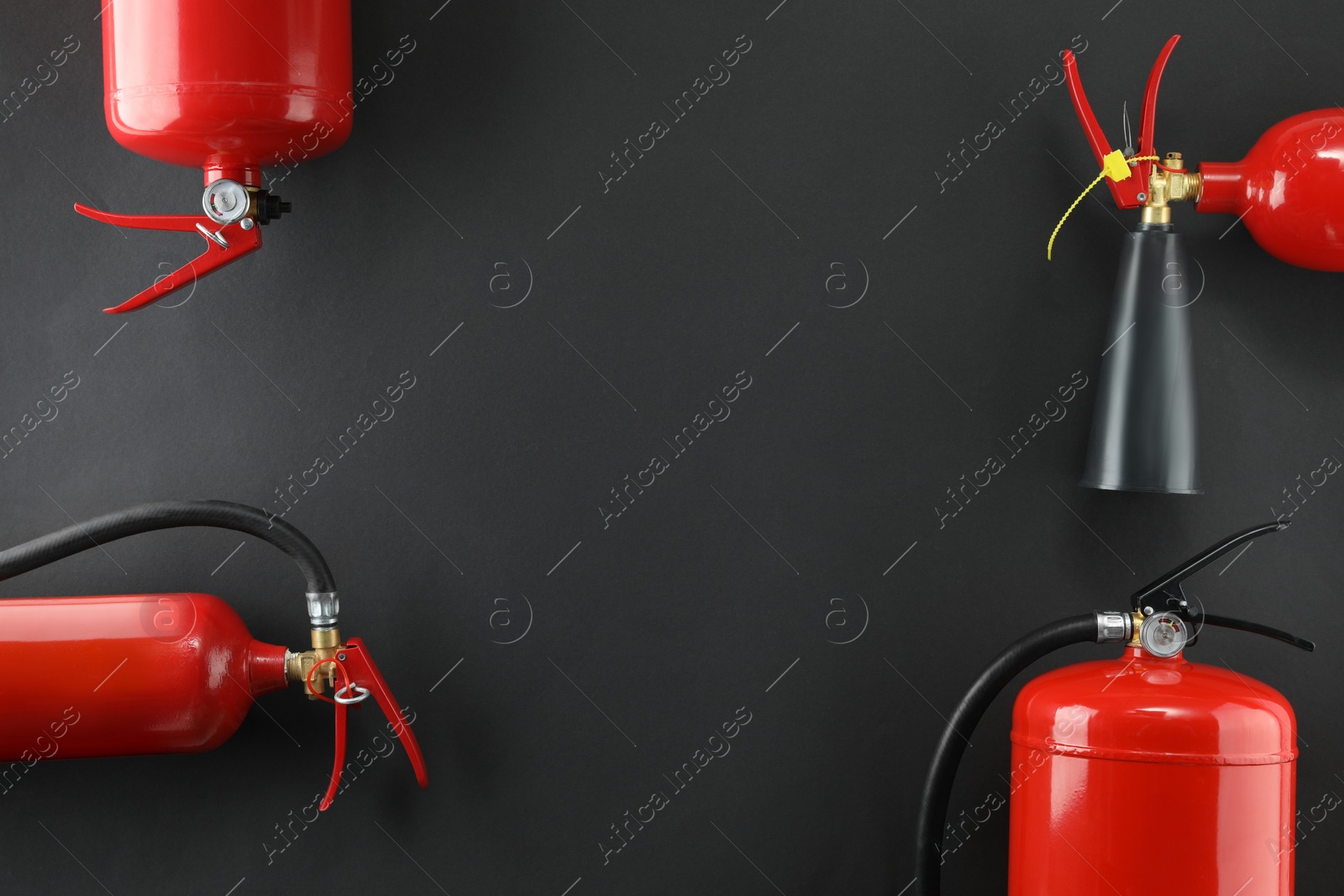 Photo of Different fire extinguishers on black background, flat lay. Space for text