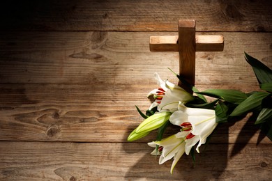 Photo of Cross and lilies on wooden background, above view with space for text. Religion of Christianity