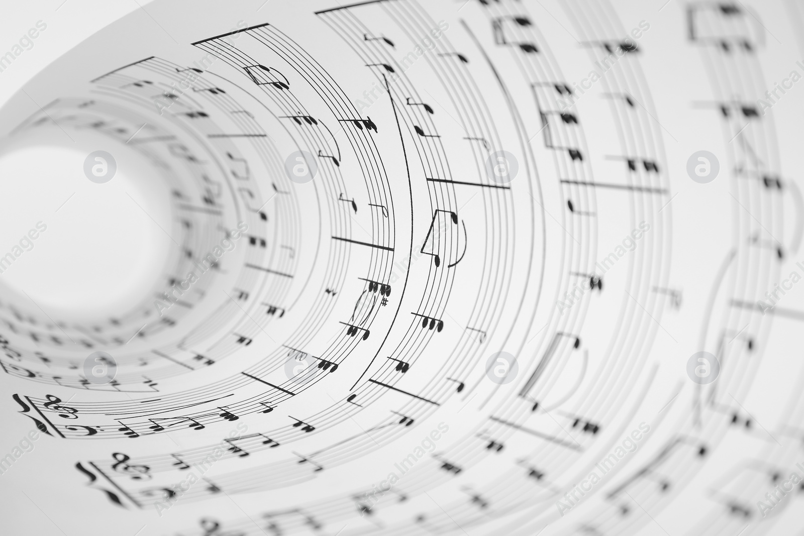 Photo of Rolled sheet with music notes on white background, closeup view