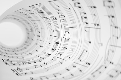 Photo of Rolled sheet with music notes on white background, closeup view