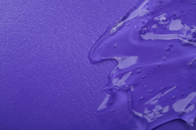 Photo of Sample of transparent cosmetic gel on violet background, top view