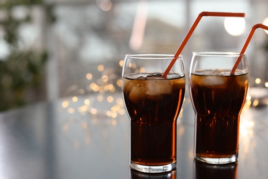 Glasses of cold cola against blurred fairy lights. Space for text