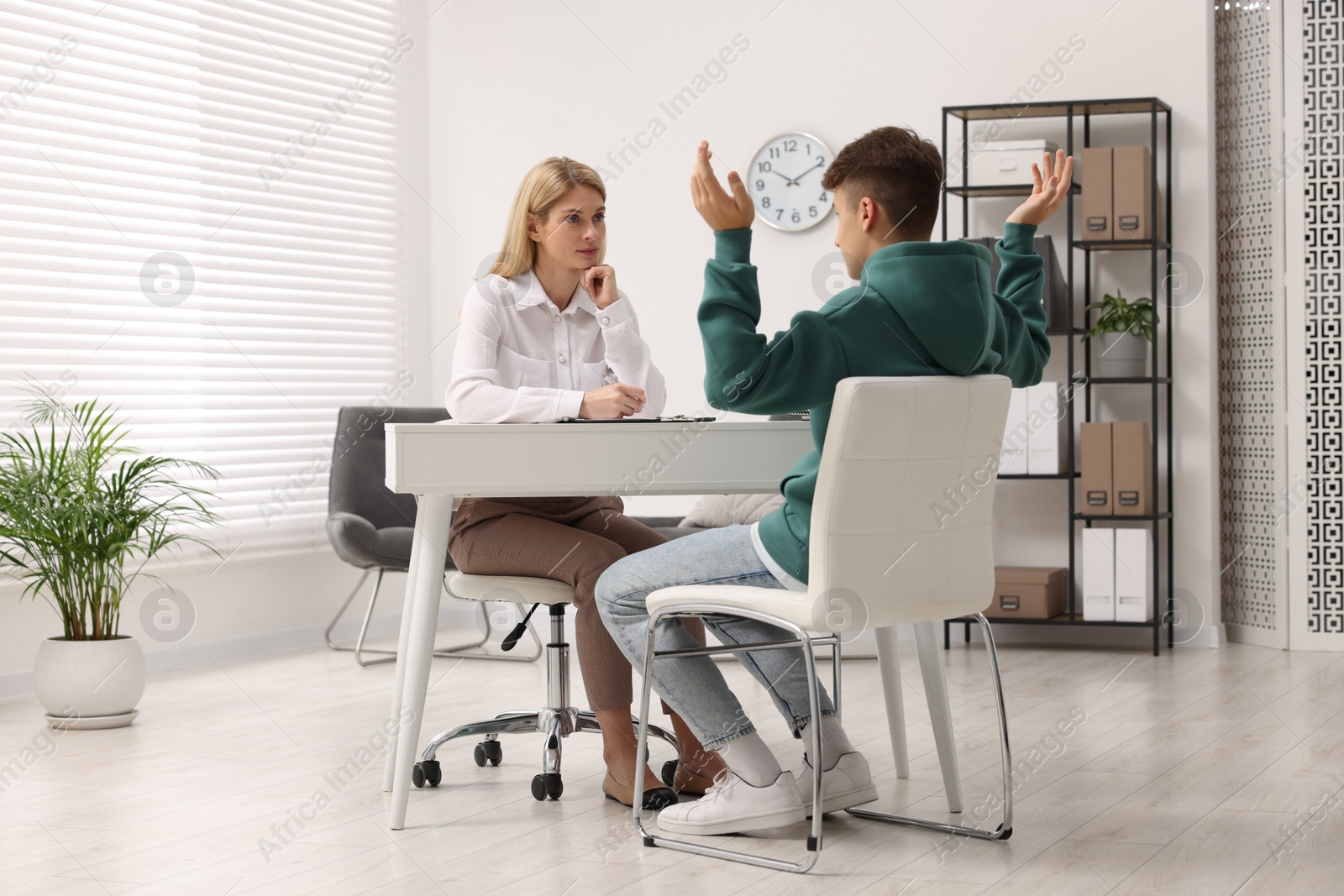 Photo of Psychologist working with teenage boy at table in office