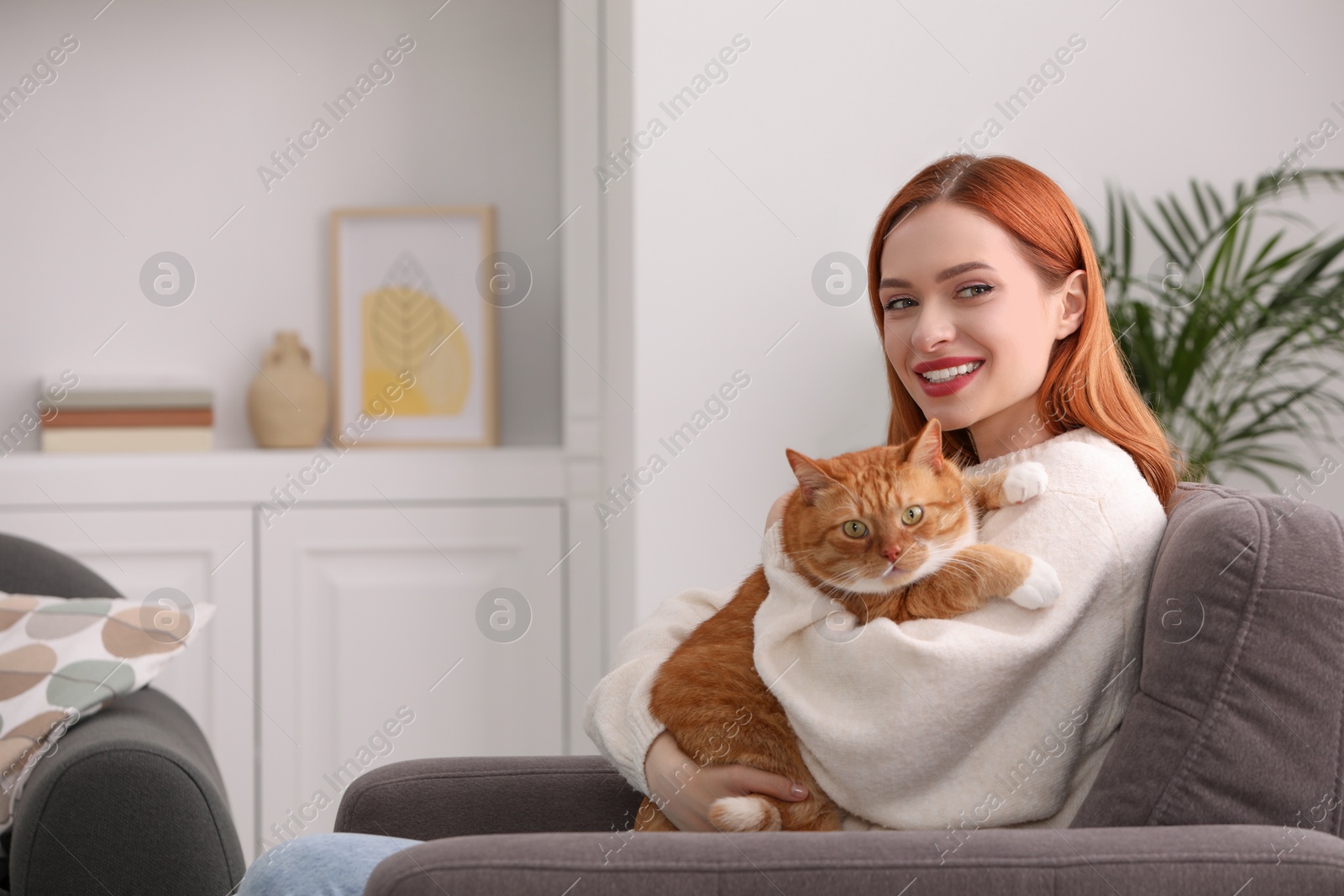 Photo of Happy woman with her cute cat in armchair at home. Space for text