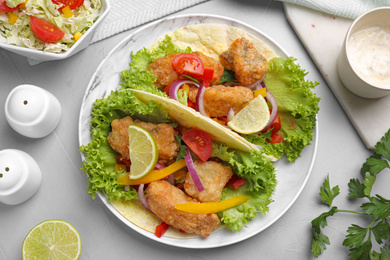 Photo of Delicious fish tacos served on light  grey table, flat lay