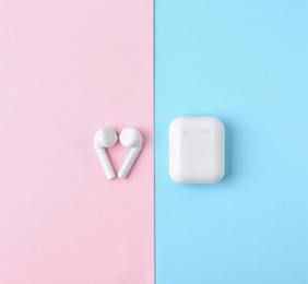 Photo of Modern wireless earphones and charging case on color background, flat lay