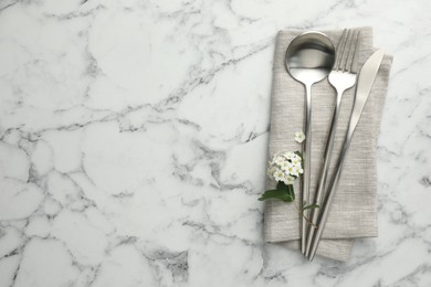 Stylish setting with cutlery and napkin on white marble table, top view. Space for text