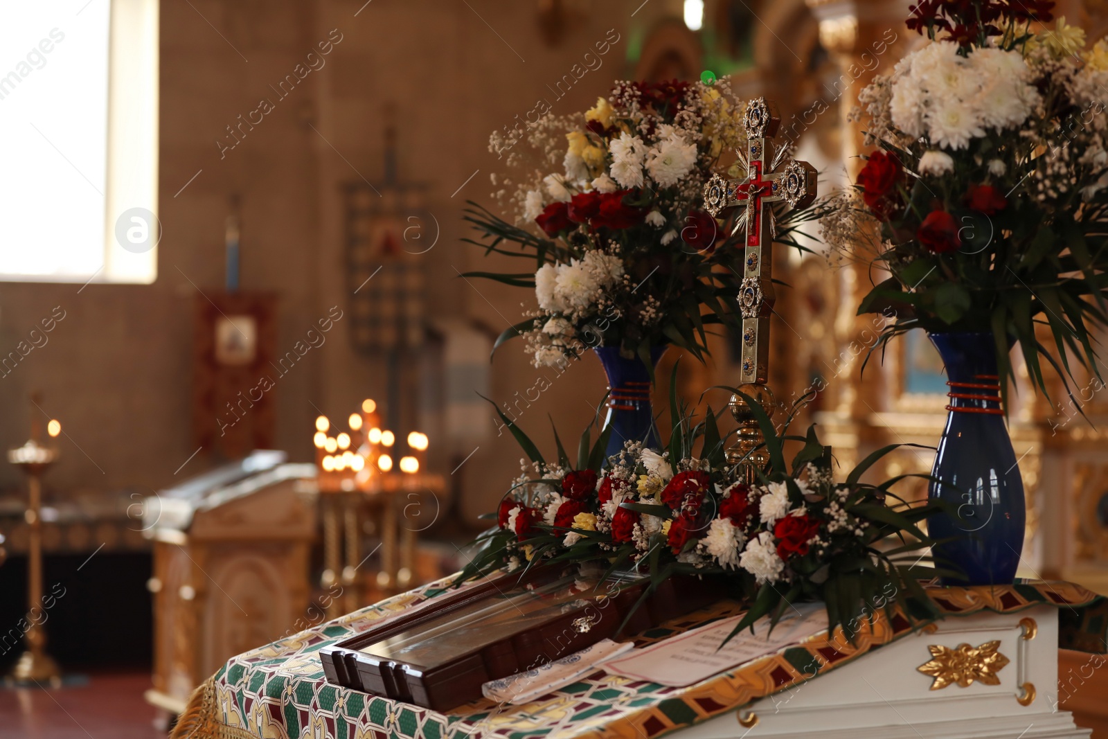 Photo of Ecclesiastical icon, cross and flowers on altar in church. Baptism ceremony