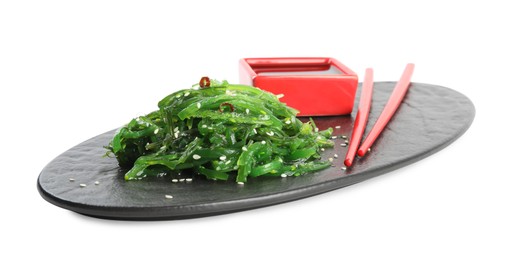 Photo of Slate plate with Japanese seaweed salad, soy sauce and chopsticks isolated on white