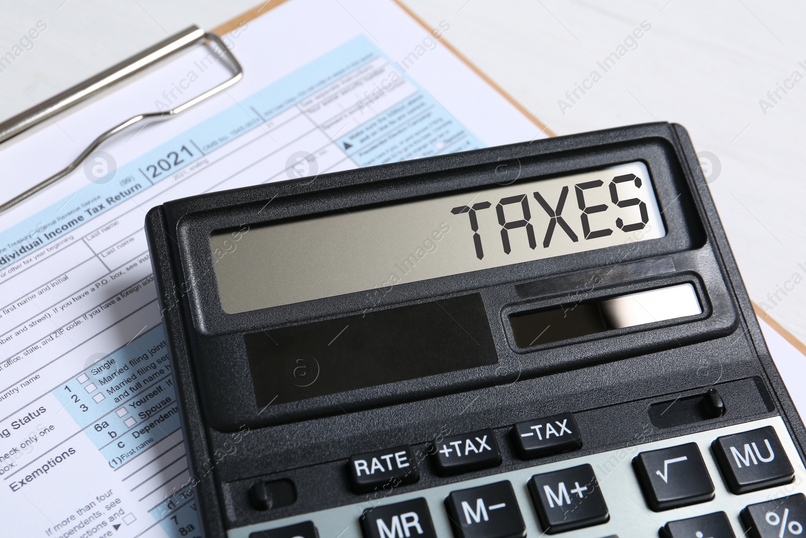 Image of Calculator with word Taxes and document on table, closeup