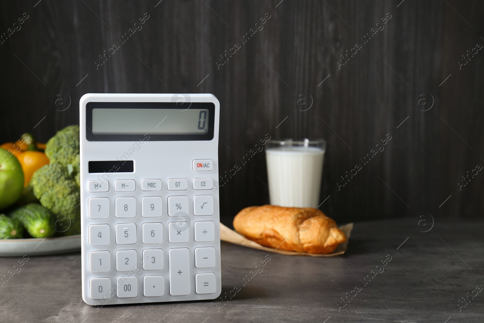 Photo of Calculator and food products on dark grey table, space for text. Weight loss concept