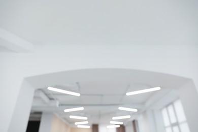 Photo of Blurred view of white ceiling with modern lighting in room