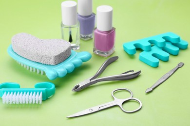 Set of pedicure tools on light green background