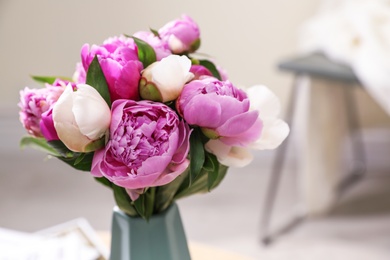 Photo of Vase with bouquet of beautiful peonies in room, space for text