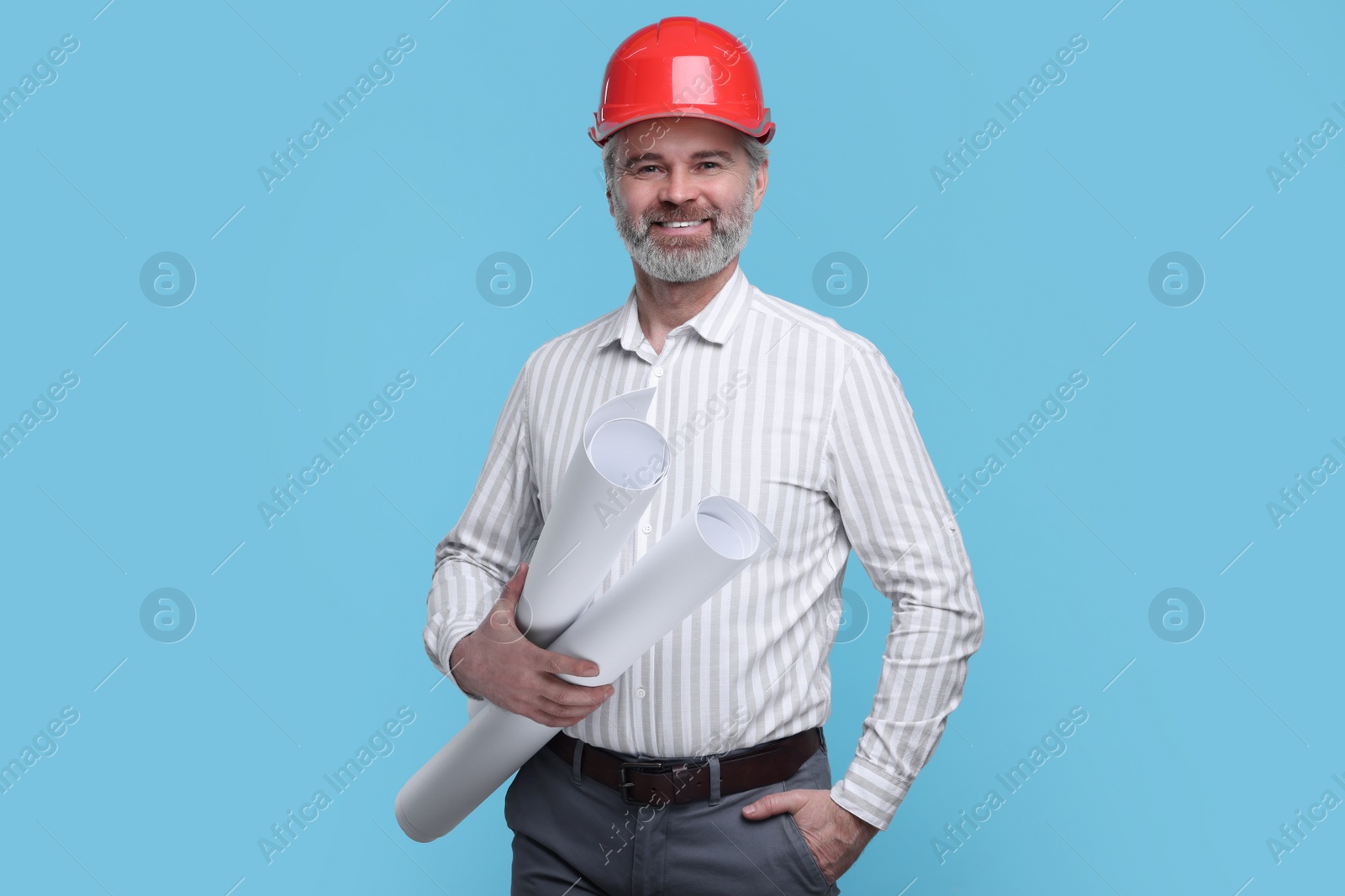 Photo of Architect in hard hat holding drafts on light blue background