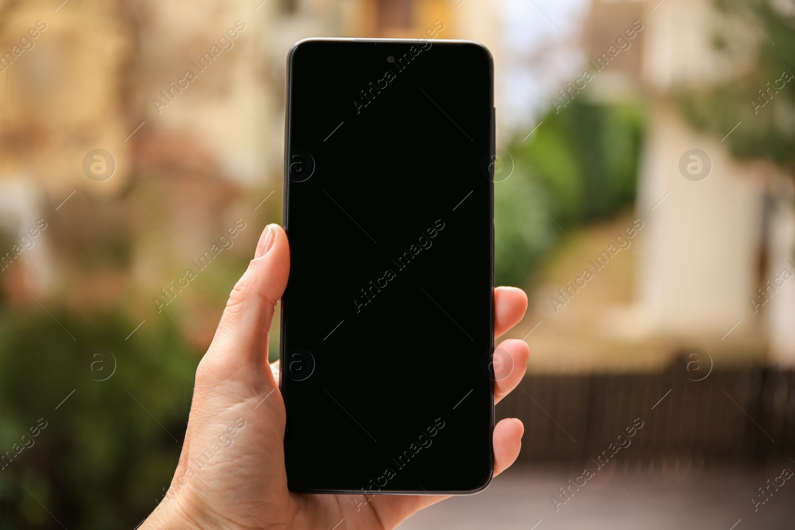 Photo of Woman holding smartphone with blank screen outdoors, closeup