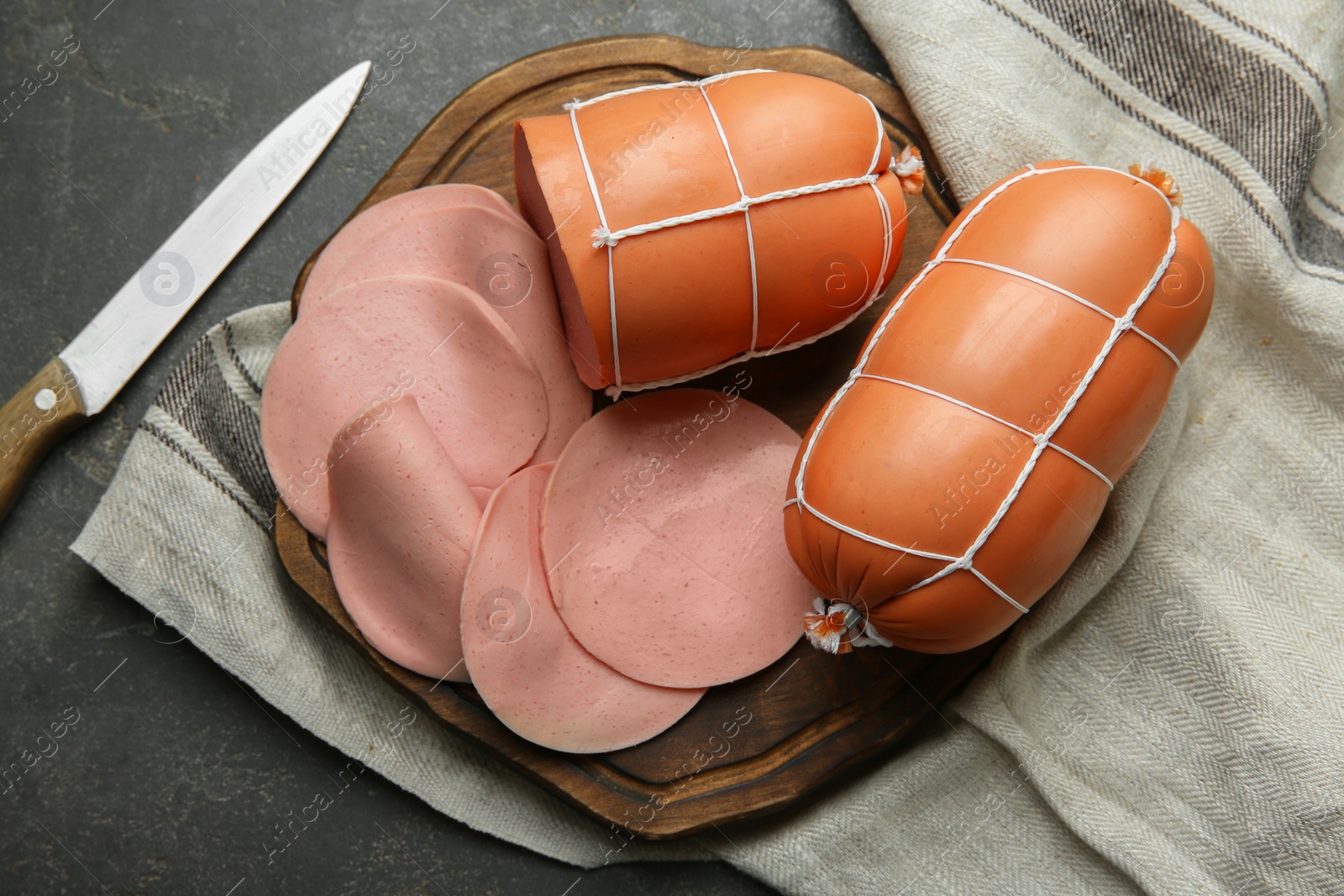 Photo of Board with tasty boiled sausages on grey textured table, flat lay