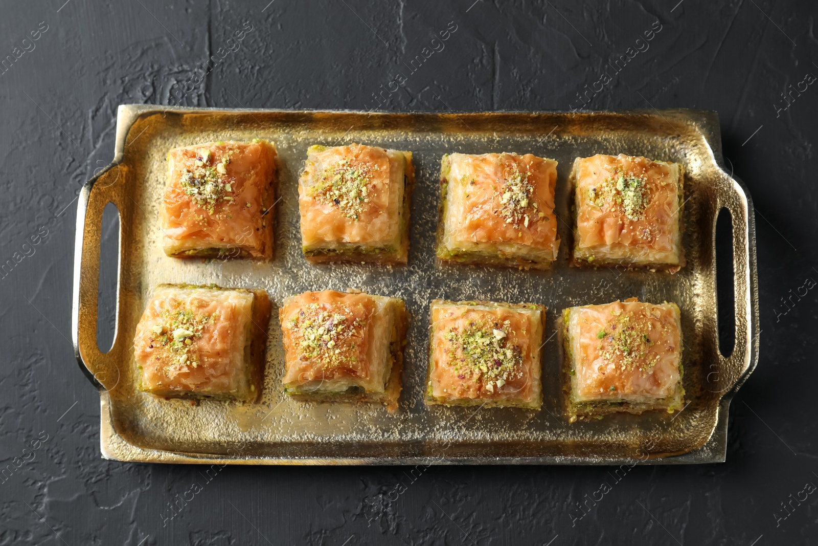 Photo of Delicious fresh baklava with chopped nuts on dark textured table, top view. Eastern sweets