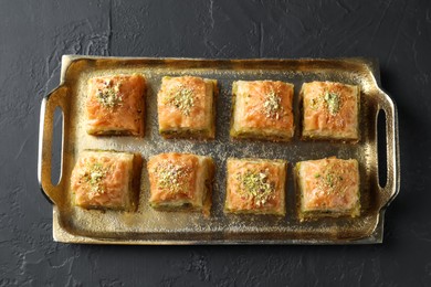 Photo of Delicious fresh baklava with chopped nuts on dark textured table, top view. Eastern sweets