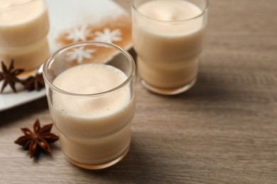 Photo of Delicious eggnog with anise on wooden table. Space for text