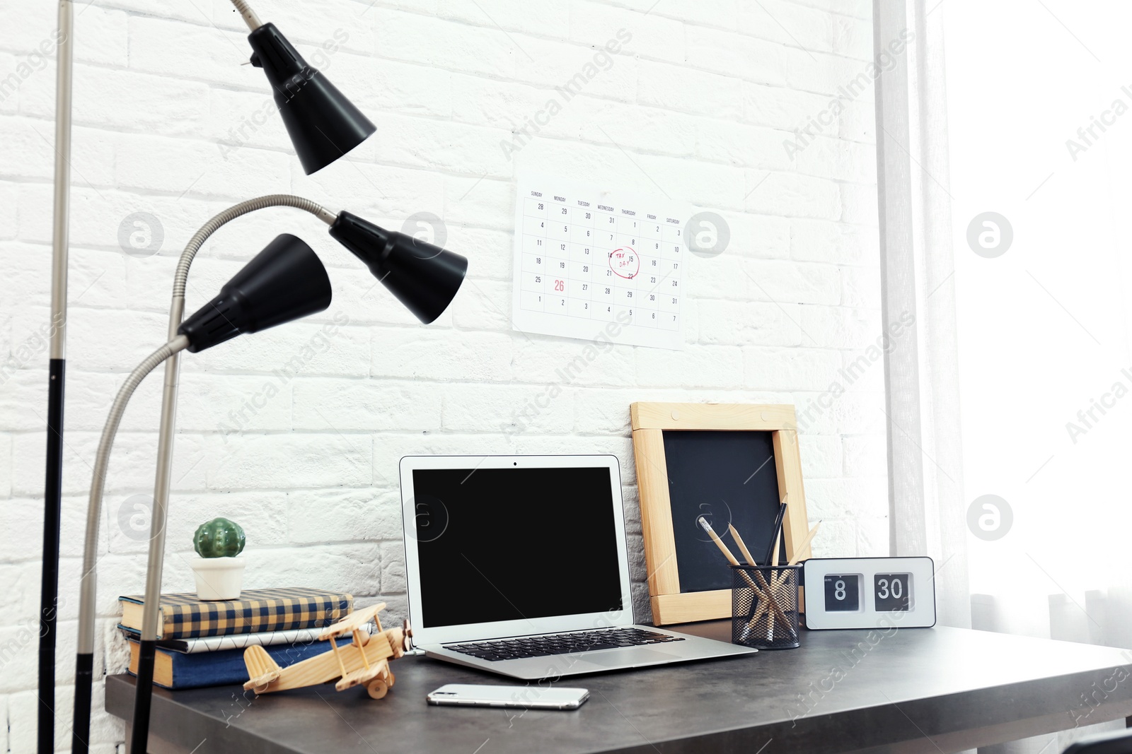 Photo of Stylish workplace with laptop on table near brick wall