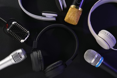 Photo of Different microphones and headphones on dark background, flat lay. Sound recording and reinforcement