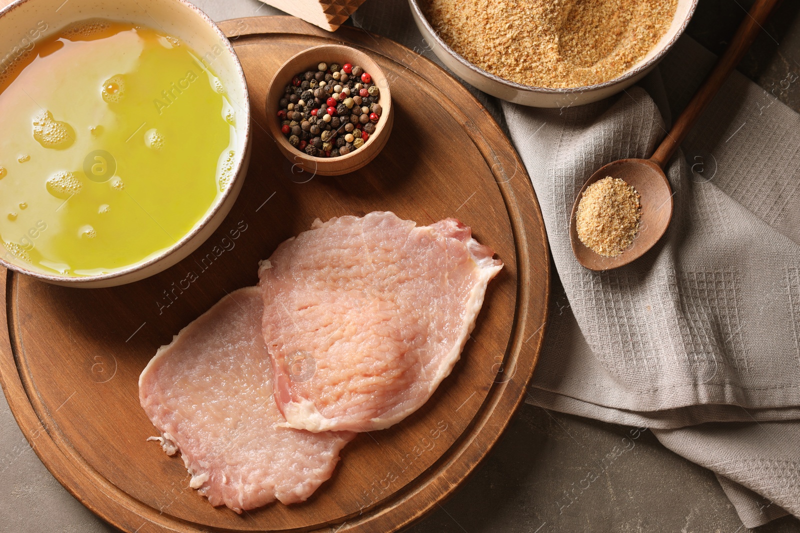 Photo of Cooking schnitzel. Raw pork slices and other ingredients on grey table, flat lay